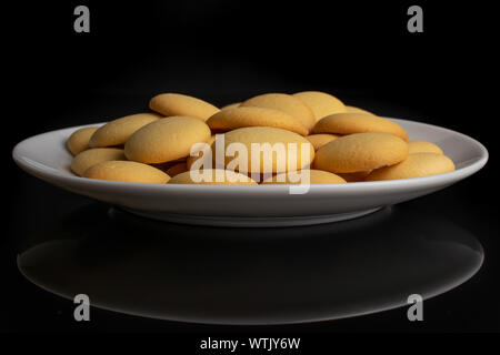 Lot of whole sweet golden sponge biscuit on white ceramic plate isolated on black glass Stock Photo