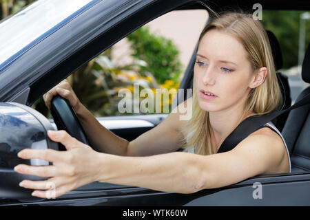 gorgeous young woman looking at car side mirror Stock Photo