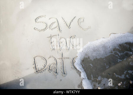 save the date, written in sand and being washed away by wave Stock Photo