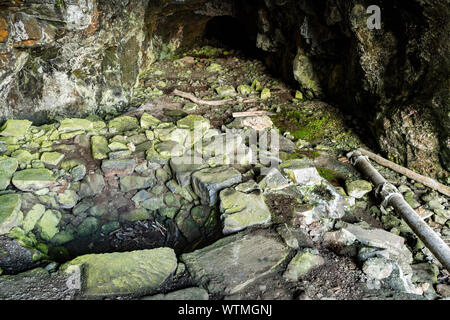 The remains of the illicit distillery still in the Whisky Cave, on the Treshnish Peninsula coast walk, Isle of Mull, Scotland, UK Stock Photo
