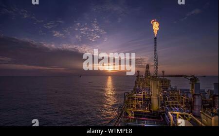Oil Rig Over Sea Against Sunset Sky