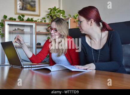 Portrait of two young women using laptop in the office Stock Photo