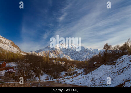 Mountain alps partially covered by snow above small village, late fall Stock Photo
