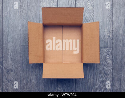 Flat lay of empty open cardboard box on wooden surface Stock Photo