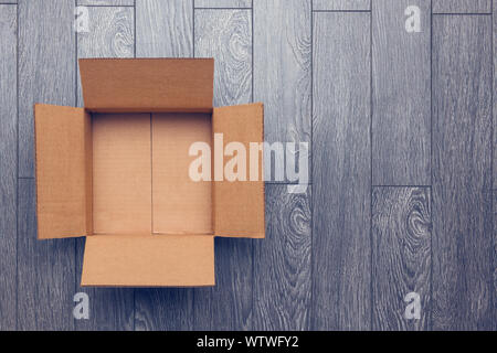 Flat lay of empty open cardboard box on wooden surface with empty space Stock Photo