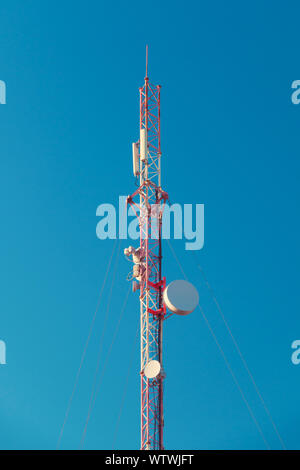 Cell tower with antennas over blue sky Stock Photo