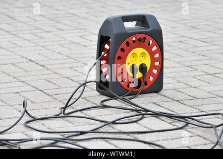 Electrical extension cord with plugs, extension lead. Electric extension cord on ground Stock Photo