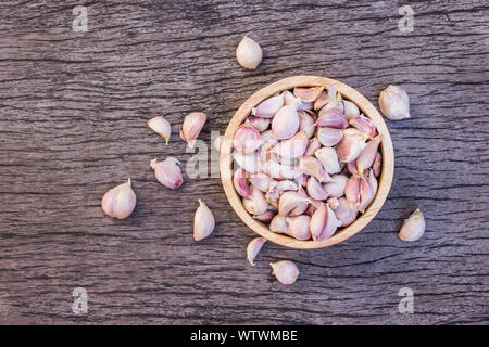 Dry garlic put in wood bowl on old wooden background. Top view Stock Photo