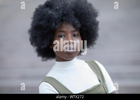 Inspired African American woman looking afar, standing on concrete stairs in the city Stock Photo