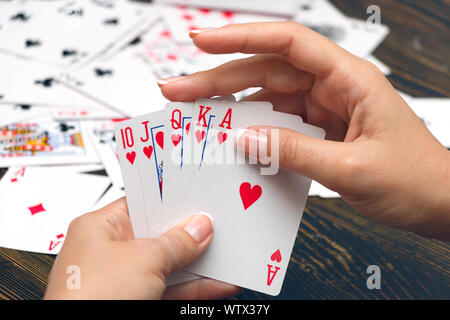 Well-conditioned female hands holding playing cards with poker strongest combination - royal flush Stock Photo