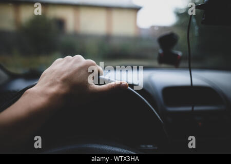 Shallow depth of field image with the hand of a driver on the steering wheel Stock Photo
