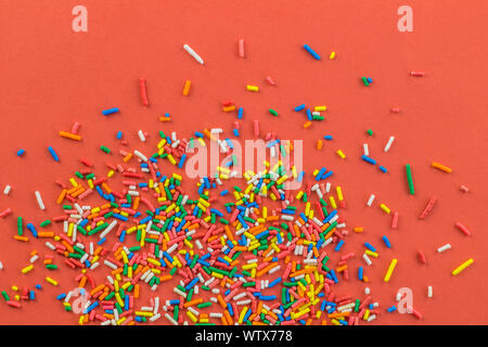 Multi-colored sprinkles on brick orange background - cake topping sprinkles - top view Stock Photo
