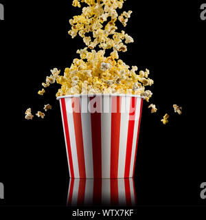 Flying popcorn from striped bucket isolated on black background Stock Photo