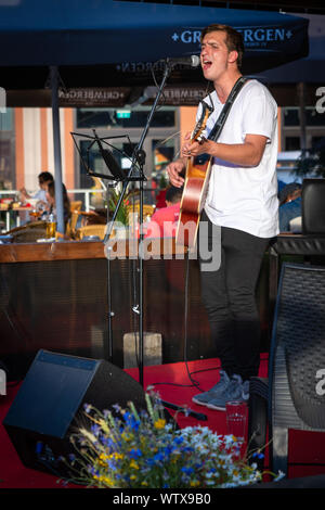 Singer From Riga Singing male vocalist performing on stage, with handheld microphone ...