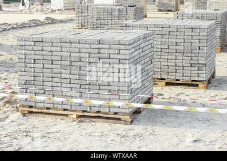 Paving grey slabs fot pavement construction in city. Gray concrete paving slabs on sand bedding to level for laying granite paver blocks Stock Photo