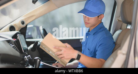 Young delivery man checking orders while preparing the products to customers Stock Photo