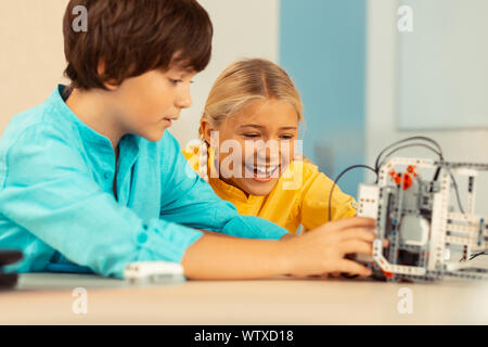 Schoolchildren being happy playing with a robot. Stock Photo