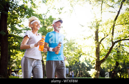 Beautiful senior couple running outside in forest Stock Photo