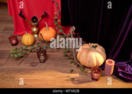 Autumn floral bouquet in a copper vase on a wooden floor decorated with pumpkins for Halloween candles. Table setting for the holiday Stock Photo
