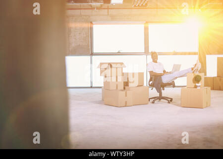 young african american casual businessman on construction site checking business workflow using laptop computer with sunlight through the windows and Stock Photo