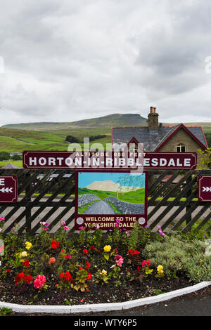 Flowerbed and station sign on the  railway station at Horton-in-Ribblesdale, North Yorkshire overlooked by distant Pen-Y-Ghent. Stock Photo