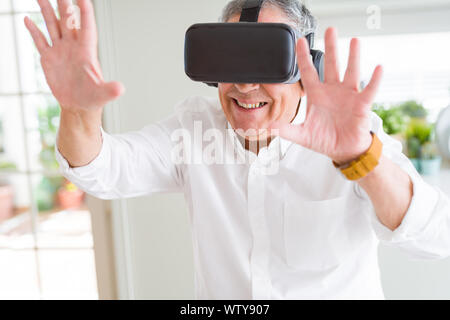 Man wearing virtual reality glasses smiling looking very happy and excited Stock Photo