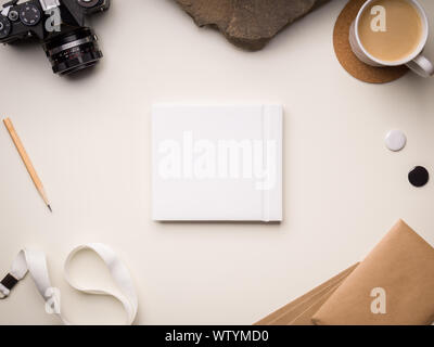 Square photo book mockup with camera and stationery on a light background Stock Photo