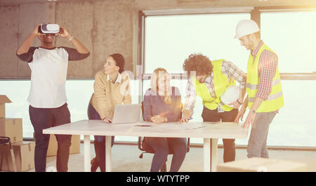 young multiethnic business team checking documents and business workflow on construction site using the virtual reality headset and laptop computer wi Stock Photo