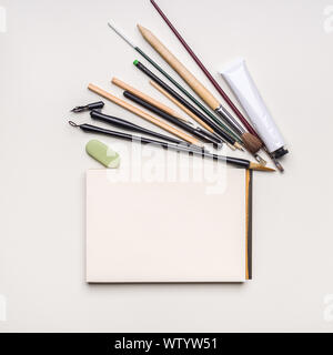 Blank flat template of an open sketchbook with various art tools on white background Stock Photo