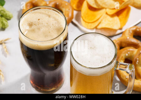 Two glasses of beer - light and dark with various snacks in the background. Close-up shot. Stock Photo