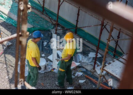 Men on the construction site performing work in uniforms. Stock Photo