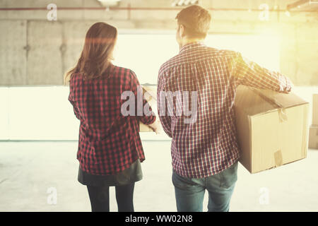 happy young casual business team carrying cardboard boxes with sunlight through the windows during moving in at new unfinished startup office building Stock Photo