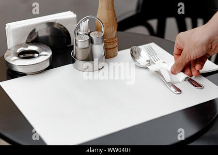 Restaurant waiter serves a table, close-up. The waiter serves empty tableware, table setting. The waitress puts the fork, sets the table Stock Photo