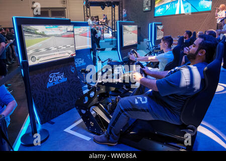 visitors play car racing game on multiple screens  in driving simulator at gamescom , world’s largest trade fair for computer and video games in Cologne, Germany on  August 21, 2019 Stock Photo