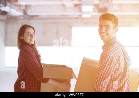 happy young casual business team carrying cardboard boxes with sunlight through the windows during moving in at new unfinished startup office building Stock Photo