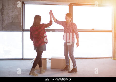 happy young casual business team carrying cardboard boxes with sunlight through the windows during moving in at new unfinished startup office building Stock Photo