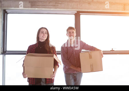 happy young casual business team carrying cardboard boxes with sunlight through the windows during moving in at new unfinished startup office building Stock Photo