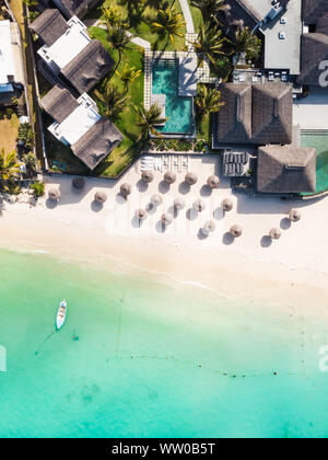 Aerial view of amazing tropical white sandy beach with palm leaves umbrellas and turquoise sea, Mauritius. Stock Photo