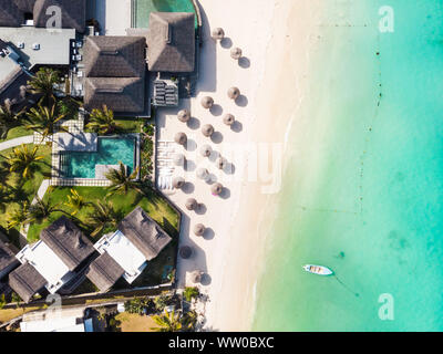 Aerial view of amazing tropical white sandy beach with palm leaves umbrellas and turquoise sea, Mauritius. Stock Photo