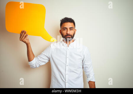 Young arab indian hispanic man holding speech bubble over isolated white background with a confident expression on smart face thinking serious Stock Photo