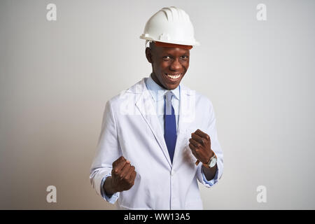 African american engineer man wearing coat and helmet over isolated white background very happy and excited doing winner gesture with arms raised, smi Stock Photo