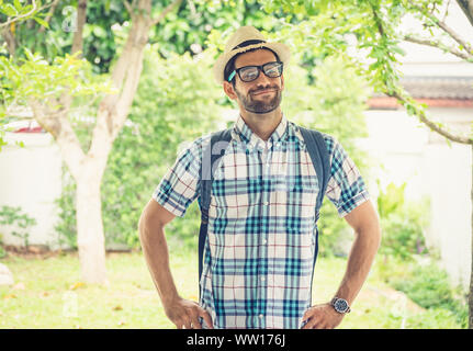Happy young bearded wearing eye glasses man carrying his backpack preparing to travel. Stock Photo