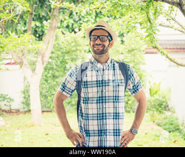 Happy young bearded wearing eye glasses man carrying his backpack preparing to travel. Stock Photo
