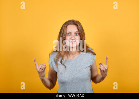 brunette girl in gray t-shirt over isolated orange background shows emotions Stock Photo