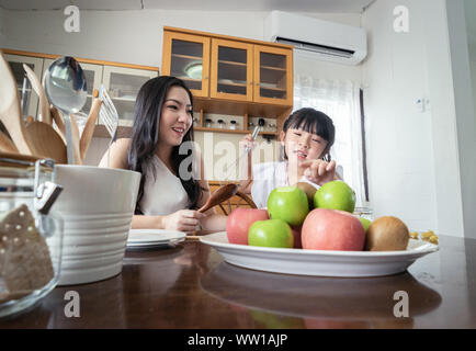 Happy moment together! Asian mother and daughter prepare their food together in the kitchen. Stock Photo
