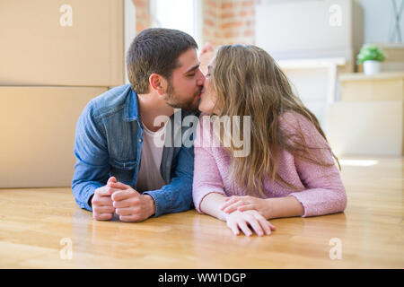 Young beautiful couple in love relaxing lying on the floor together with cardboard boxes around for moving to a new house Stock Photo