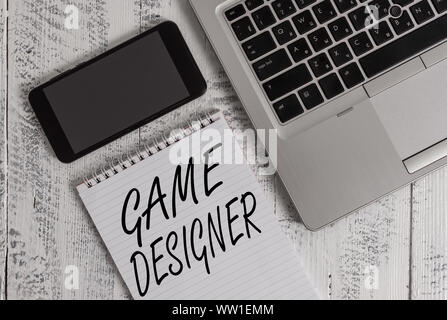 Handwriting text Game Designer. Conceptual photo Campaigner Pixel Scripting Programmers Consoles 3D Graphics Metallic laptop blank ruled notepad smart Stock Photo