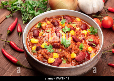 Chili con carne, a traditional Mexican dish with red beans, cilantro leaves, ground meat, and chili peppers, a closeup with ingredients Stock Photo