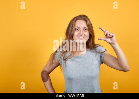 brunette girl in gray t-shirt over isolated orange background shows emotions Stock Photo