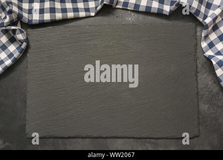 Black slate background with kitchen blue checkered towel. Cooking food, pizza table, picnic or food background with copy space for text. Top view. Stock Photo